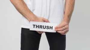 man grabbing crotch holding sign saying 'thrush' in front